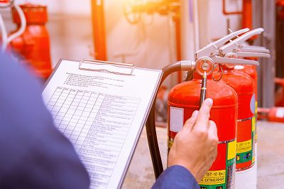 A man counting the fire extinguishers with a clip board